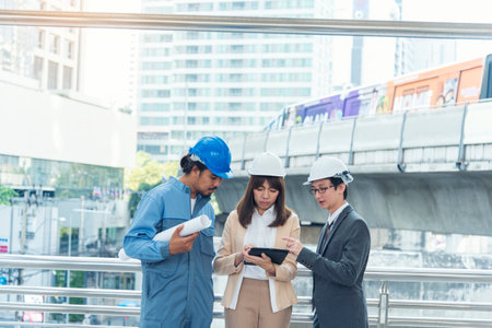 Civil engineer teams meeting working together wear worker helmets hardhat on construction site in modern city. Foreman industry project manager engineer teamwork. Asian industry professional teamの写真素材