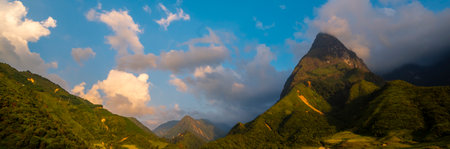 Banner Beautiful landscape mountain green field grass meadow white cloud blue sky on sunny day. panoramic Majestic green scenery big mountain hill cloudscape valley panorama view greenery countrysideの写真素材