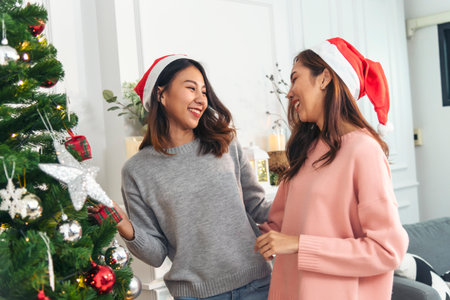 Two Women siblings using hands decorate Christmas tree red ball, bauble, snow flake. Close up hands...