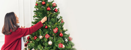 Banner Woman hands decorate Christmas tree red ball bauble. Panorama hands holding red ball bauble decorate. Wide shot Asian woman decor christmas tree in xmas season celebration with Copy Spaceの写真素材
