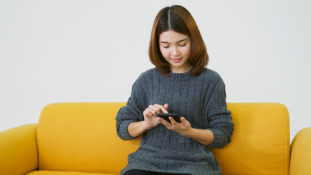 Asian woman holding smartphone with E-commerce Shopping online website Reading Online Article, Blog, vlog. Young Woman hands holding phone technology lifestyle. Happy Woman using digital smart phoneの写真素材