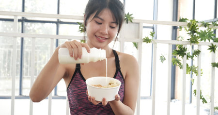 Women hands holding white glass of milk pouring from bottle. Asian women smile laugh look at camera health care home fitness lifestyle. Beautiful female drinking fresh milk low-fat dairy free lactoseの写真素材