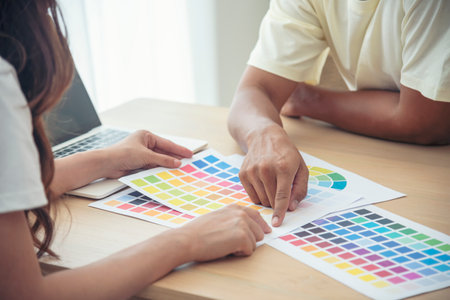 Interior designer team partner engineer brainstorming choosing color swatch. Asian Engineer man contractor brainstorming teams partner meeting together. Paint palette architecture plan in office deskの写真素材