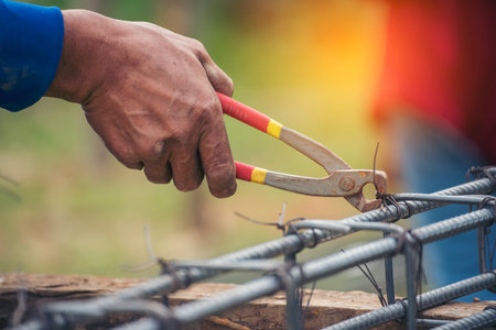 Construction Worker hands using pincer pliers iron wire. Outdoor Worker using wire bending pliers, construction work. Men hands bending cutting steel wire fences bar reinforcement of concrete workの写真素材