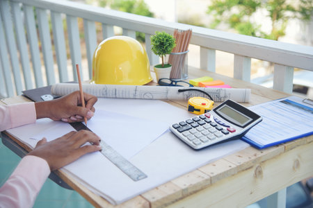 Civil construction engineer working with laptop at desk office with white yellow safety hard hat at...