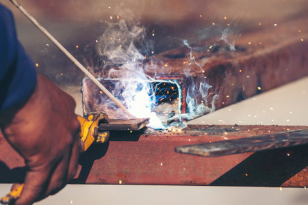 Construction Worker hands using Welding machinery iron metal sparking. Men hands wear protective...