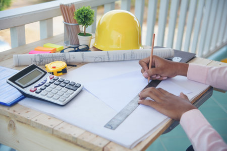 Civil construction engineer working with laptop at desk office with white yellow safety hard hat at...