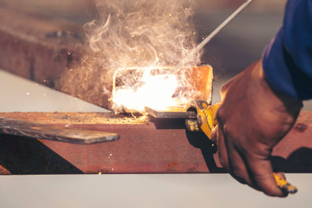 Construction Worker hands using Welding machinery iron metal sparking. Men hands wear protective glove Hot flame metal work cutting fire iron workshop. Locksmith use Welding machine cut metal processの写真素材