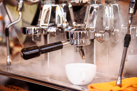 Close up hands coffee barista man make hot cup espresso shot from coffee machine. Cappuccino with milk in italian coffee shop cafe. Close up hands of barista use machine make black drinking hot cupの写真素材