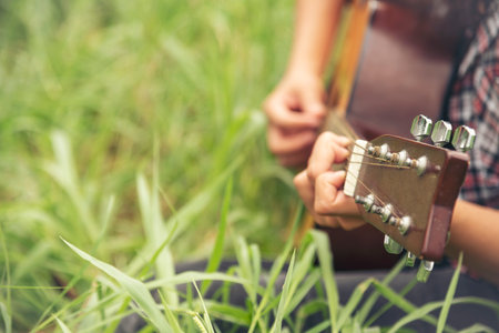 Young women playing acoustic guitar outdoor in green park. Woman person playing acoustic guitar music instrument at home, young Asian musician girl lifestyle in beautiful nature. Happy guitaristの写真素材