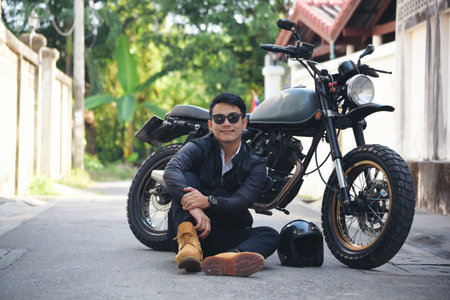 Asian man with a motorbike in black leather jacketの写真素材