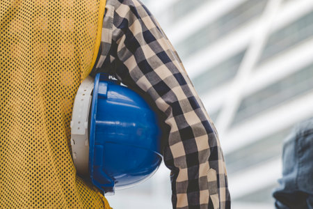 Engineer man hands holding hardhat white work helmet hard hat for Civil Construction Engineering. Construction engineer man in safety suit hold white work helmet hard hat on hands at Construction Siteの写真素材