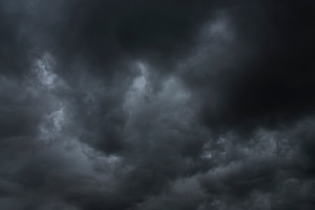 Dramatic dark storm rain clouds black sky background. Dark thunderstorm clouds rainny atmosphere. Meteorology danger windstorm disasters climate. Dark cloudscape storm disaster gloomy gray cloud skyの写真素材