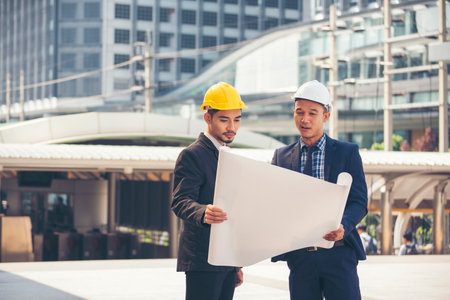 Two men engineer look at blueprint architecture building contractor design in modern city...