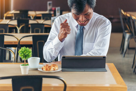 Businessman using smart digital tablet at office desk via wireless internet technology working online. Asian handsome man hold smart tablet use gadget check news. Freelance business person technologyの写真素材