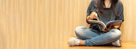 Banner Asian woman holding book reading at university library. Panorama Young woman relaxation read open book. University women self study at library bookstore. Women self learning with copy spaceの写真素材