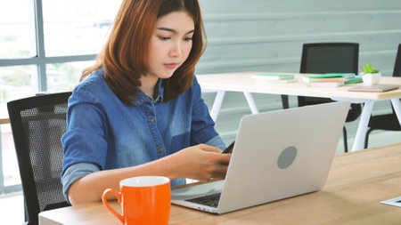 Happiness Asian Woman working from home using laptop online meeting in home office. Happy relax time asian business woman typing keyboard use notebook laptop Smiling, laughing at home office.の写真素材