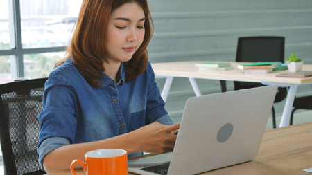 Happiness Asian Woman working from home using laptop online meeting in home office. Happy relax time asian business woman typing keyboard use notebook laptop Smiling, laughing at home office.の写真素材