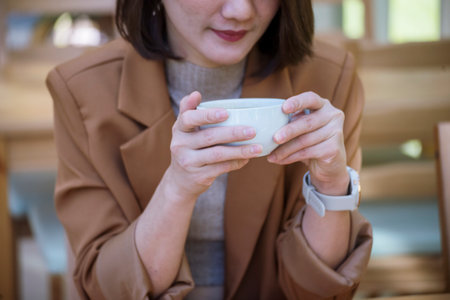 Close up Woman hand holding black coffee cup in green garden cafe. Hands of businesswoman love drinking hot coffee. business women with black coffee or hot chocolate in coffee shop. Caffeine drinkingの写真素材