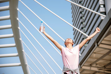 Women drinking water bottle running exercise in modern city wear wellness sportswear outside. Young...