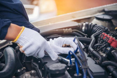 Close up Car Mechanic man hands repairing car auto repair shop. Man hands fixing machinery vehicle...