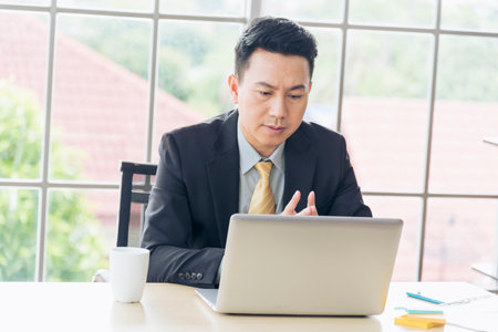 Asian Businessman using laptop at office desk. Man hands typing computer keyboard reading financial graph chart Planning analyzing marketing data. happy Asian business men people working office firmの写真素材
