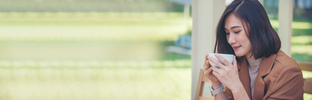 Banner Asian Woman drink black coffee hand holding cup at garden cafe.の写真素材