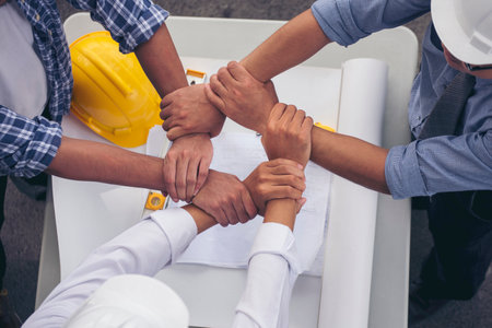 Close up engineer men hands diversity multiethnic partners team together. Group of multiracial people Engineer Manager Foreman Teamwork meeting join hands. Top view office table team join partnershipの写真素材
