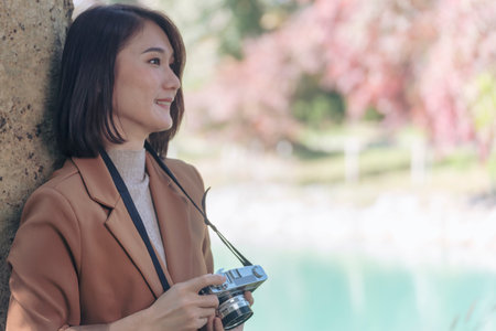 Asian Women with vintage film camera take a photo. Smiling female photographer look at photo from...