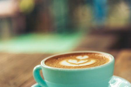 Latte art coffee cup with milk on wooden table. Espresso shot make latte art hot coffee cup. Cappuccino with milk in italian coffee shop cafe. Brown hot caffeine beverage in cafeteria with copy spaceの写真素材