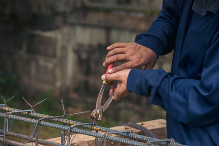 Men hands using pincer pliers iron wire reinforcement of concrete work. Construction Worker hands bending cutting steel wire fences bar. Outdoor Worker using wire bending pliers, construction work.の写真素材