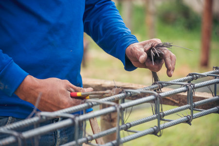 Men hands using pincer pliers iron wire reinforcement of concrete work. Construction Worker hands bending cutting steel wire fences bar. Outdoor Worker using wire bending pliers, construction work.の写真素材