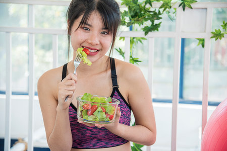 Wellness Asian women dressing organic green salad tomato vegetable dish. Beautiful girl healthcare vegan wellness lifestyle concept. Healthy woman workout holding organic salad bowl healthy lifestyleの写真素材