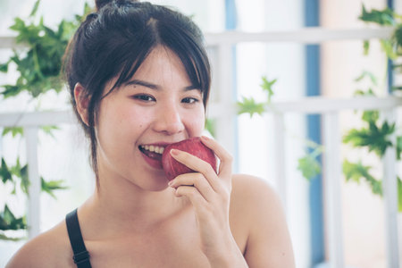 young asian woman eating Apple Healthy. Girl workout holding organic apple fruit healthy lifestyle. Wellness Asian women eat red apple smile face look at camera. Beauty health care lifestyle conceptの写真素材