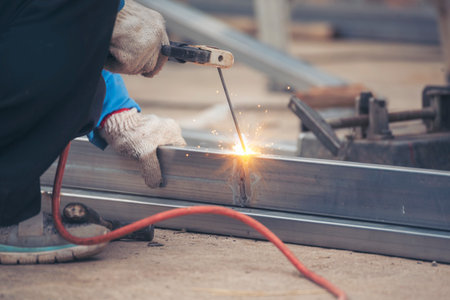 Construction Worker hands using Welding machinery iron metal sparking. Men hands wear protective...