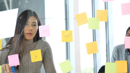 Diversity multi ethnic group brainstorming teams with business partner meeting and share ideas in conference room. Creative design colleague talking strategy plan use sticky notes post, present ideasの写真素材