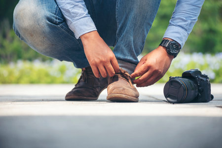 Man kneels down rope tie shoes industry boots for worker. Close up shot of man hands tied shoestring...