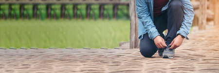 Banner Man kneels down rope tie shoes industry boots for worker. Close up shot of man hands tied...