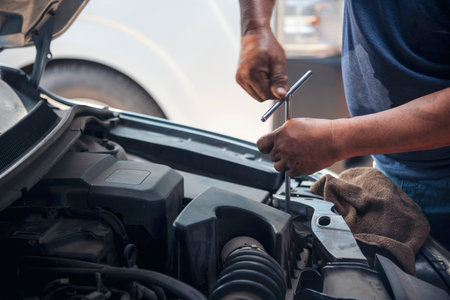 Close up Car Mechanic man hands repairing car auto repair shop. Man hands fixing machinery vehicle mechanical service. open vehicle hood checking up auto mobile. Vehicle Car maintenance engineer.の写真素材