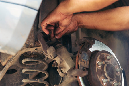 Close up Car Mechanic man hands repairing car auto repair shop. Man hands fixing machinery vehicle mechanical service. open vehicle hood checking up auto mobile. Vehicle Car maintenance engineer.の写真素材