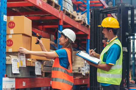 Warehouse management team use bar code scaner scan goods shelf writing checklist on clipboard. Asian...