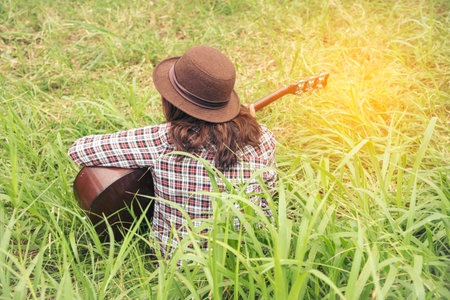 Young women playing acoustic guitar outdoor in green park. Woman person playing acoustic guitar music instrument at home, young Asian musician girl lifestyle in beautiful nature. Happy guitaristの写真素材