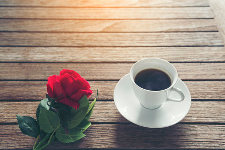 Tabletop black coffee cup red rose on wood table background with empty copy space. Espresso shot caffeine hot coffee cup in cafe. Top view Black caffeine dark beverage in cafeteria with copy spaceの写真素材