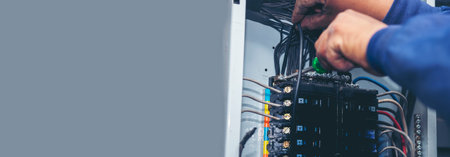 Banner Electrical mechanic technician check wire electric cabinet. Inspector men hands working maintenance service. Electrician circuit repair operation. Men hands fix breaker with copy spaceの写真素材