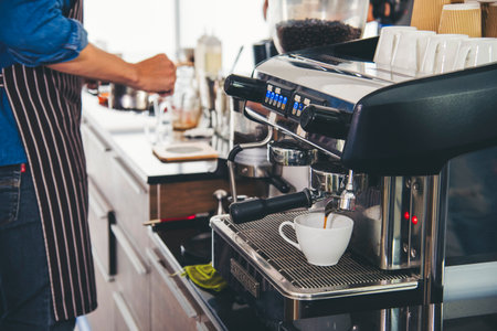 Close up hands coffee barista man make hot cup espresso shot from coffee machine. Cappuccino with milk in italian coffee shop cafe. Close up hands of barista use machine make black drinking hot cupの写真素材