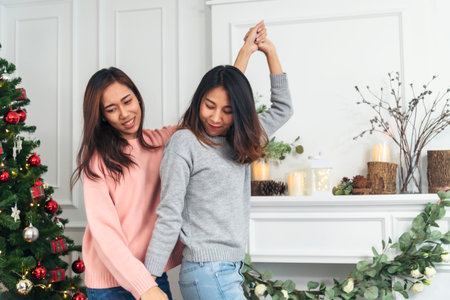 Christmas party Women friendship dance together with happiness. Asian Young women enjoy laughing dancing party together in living room to celebrate Christmas holiday countdown Happy New Year festivalの写真素材