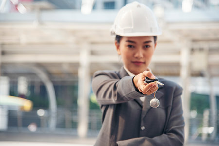 Civil women engineer wear safety white hard hat Hands using remote control car key. Close up hands of young woman showing key of new car. Businesswoman holding car rental key vehicle dealership.の写真素材