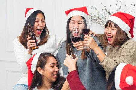 Christmas party Group of Asian Woman drink beer champagne exchange christmas gift box under xmas tree. Young women enjoy laughing sitting party together living room to celebrate Christmas holidayの写真素材
