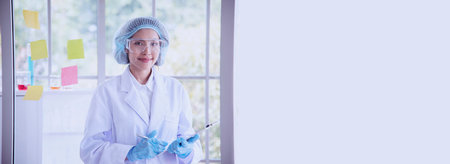 Banner Asian woman scientist hand write note research in medical lab look at science microscope. Panorama biology chemistry lab. Asian Female technician laboratory using microscope with copy spaceの写真素材
