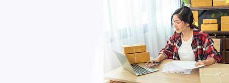 Banner Online seller Close up hands Young asian woman typing laptop keyboard checking online order on stock delivery package. Asian woman startup small business at home office with copy spaceの写真素材